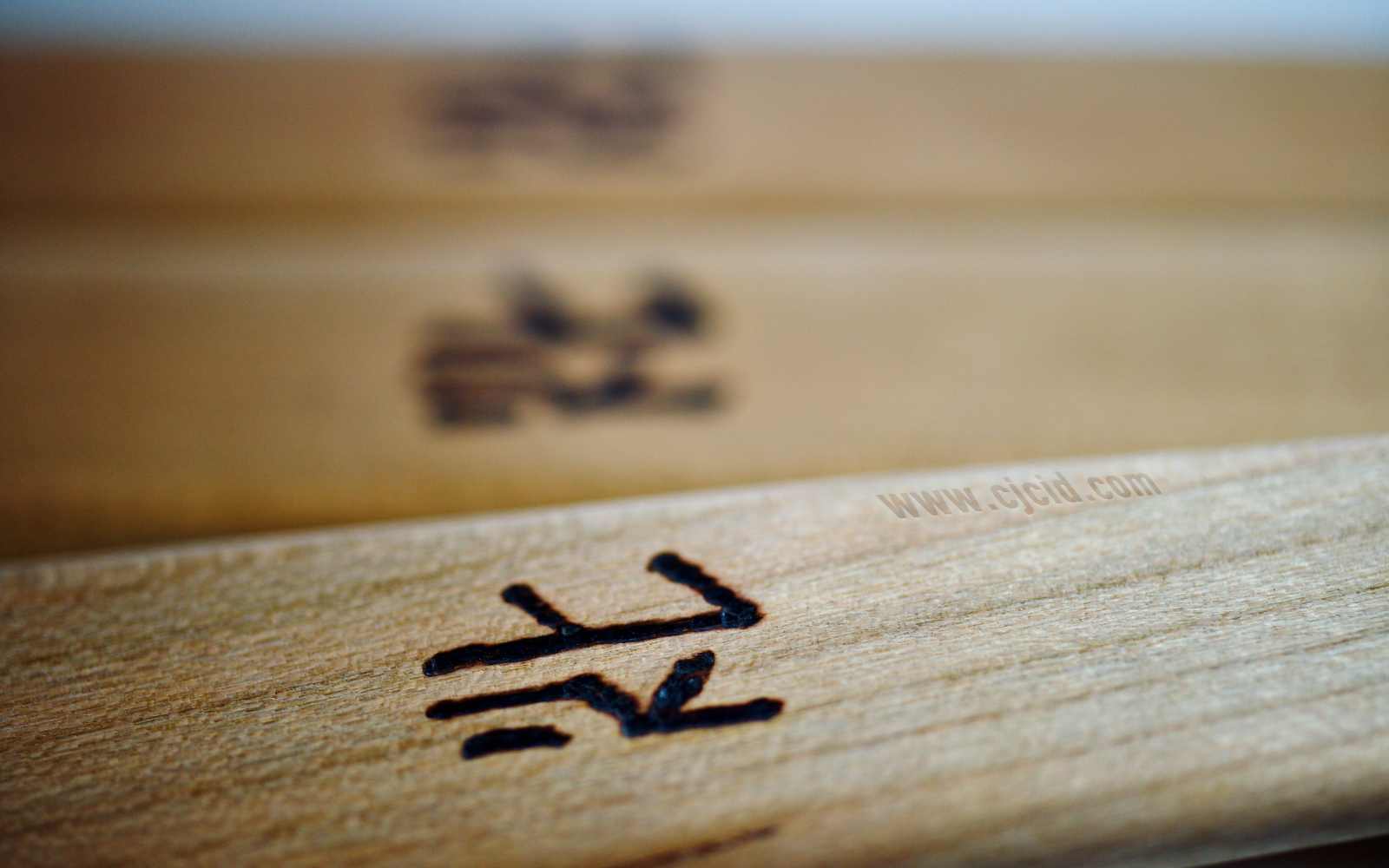 Close up on the neck’s engraved stamp of three cooking spatulæ, made from single block of solid Sakura wood